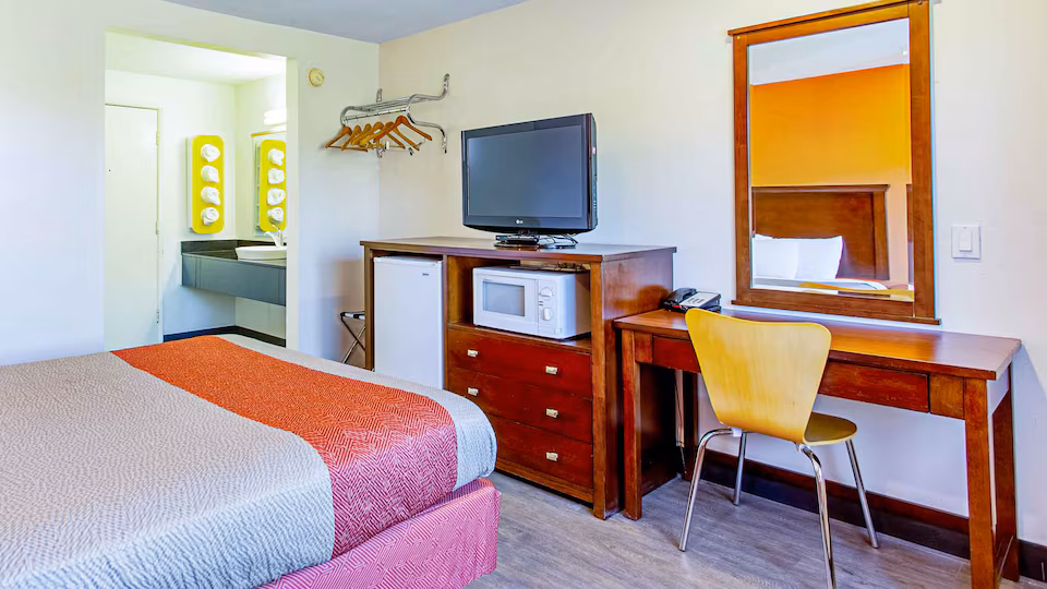 Queen room with desk, television, microwave, and refrigerator